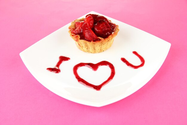 Sweet cake with strawberry and sauce on plate on color background