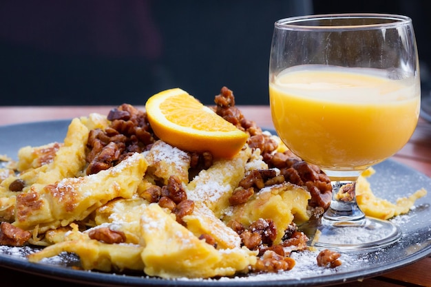 Sweet cake with walnuts, raisins, powdered sugar, orange slice on top and cream liquor glass