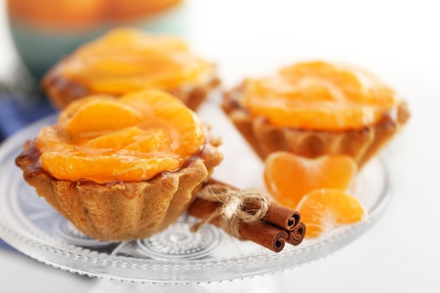 Sweet cakes with tangerines on table close up