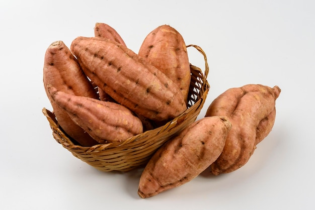 Sweet carrot potatoes in a basket isolated on white background