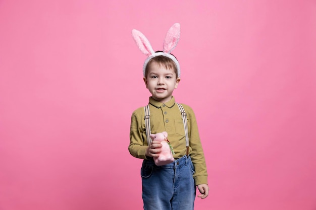 Sweet cheerful young boy posing with a fluffy rabbit toy on camera