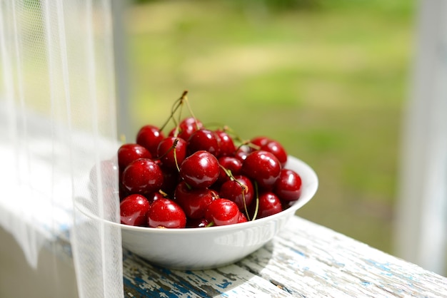 Sweet cherry Red cherry berries in white plate in garden Plate with sweet cherry berries closeup