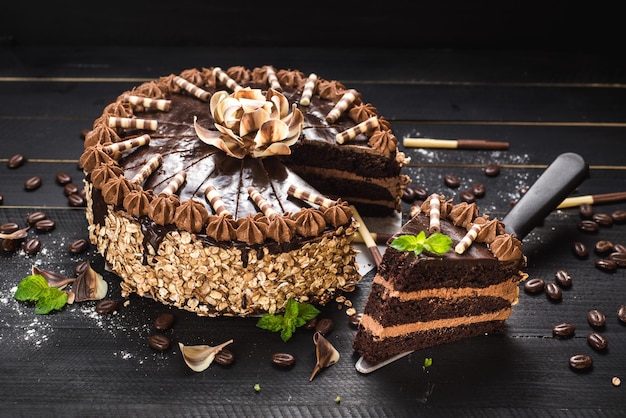 Sweet chocolate cake with tasty cream on the black wooden background