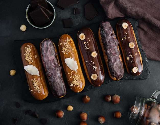 Sweet chocolate eclairs on black wooden board