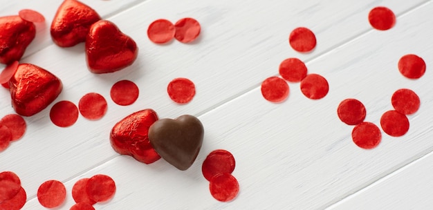 Sweet chokolate in shape of red heart on the woden white background Love concept Banner