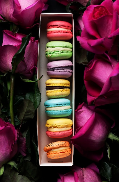 Sweet colorful macaroons and roses on black background