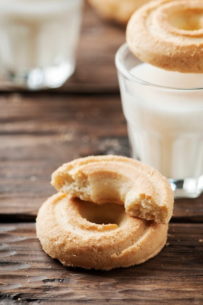 Sweet cookies and glasses of milk on wooden table