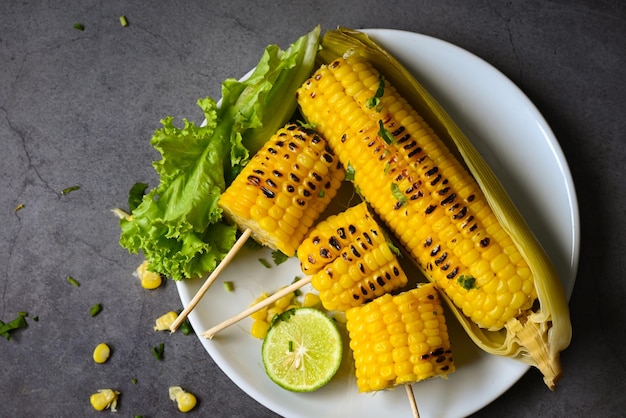 Sweet corn cooked on white plate sweet corn food with salad vegetable lime coriander and lettuce ripe corn cobs grilled sweetcorn for food vegan dinner or snack