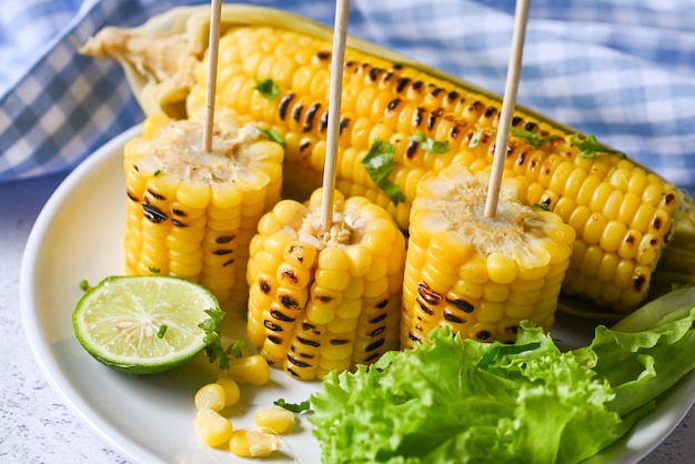 Sweet corn cooked on white plate sweet corn food with salad vegetable lime coriander and lettuce ripe corn cobs grilled sweetcorn for food vegan dinner or snack