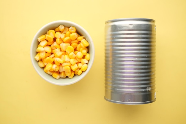 Sweet corns in a bowl with a tin container on yellow background