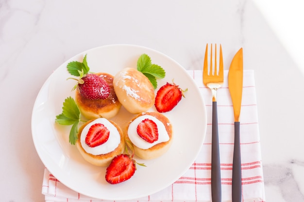 Sweet Cottage cheese pancakes on plate served with strawberries. Russian syrniki, ricotta fritters or curd fritters.