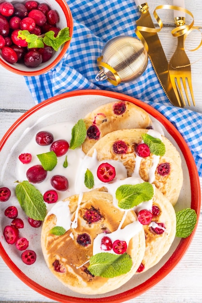 Sweet cranberry pancakes for winter breakfast or brunch Festive Christmas New Year breakfast dessert with vanilla creamy topping and fresh cranberries copy space