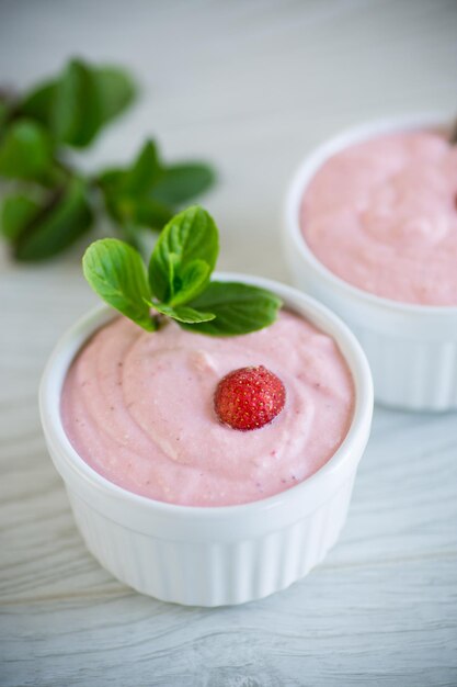 Sweet curd mass whipped with fresh strawberries in a bowl on a wooden table