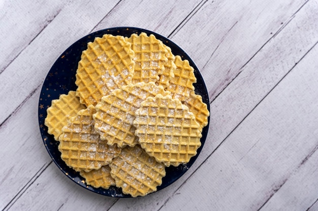 Sweet delicious crispy waffles sprinkled with powdered sugar on plate