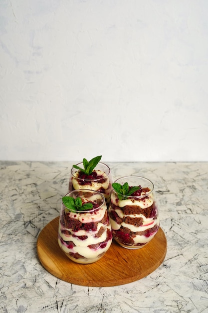 Sweet dessert with brown chocolate and white cream in a transparent glass The cake is decorated with a mint leaf birthday portioned cake