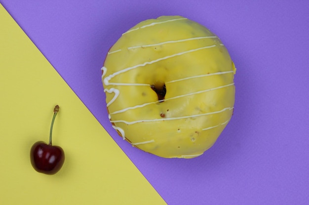 Sweet donut glazed with red cherries on a colorful background Closeup View from above