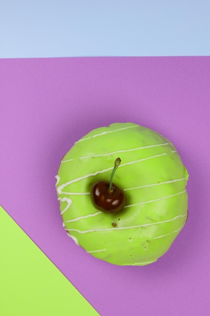 Sweet donut glazed with red cherries on a colorful background Closeup View from above