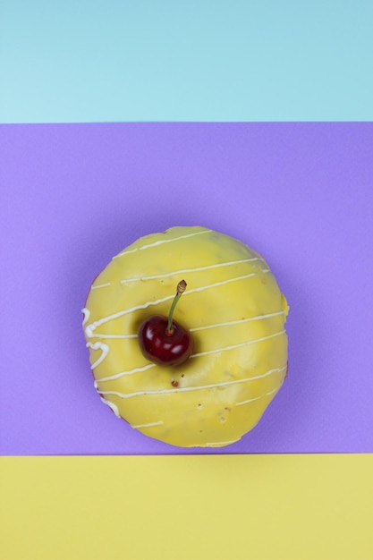 Sweet donut glazed with red cherries on a colorful background Closeup View from above