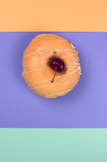 Sweet donut glazed with red cherries on a colorful background Closeup View from above