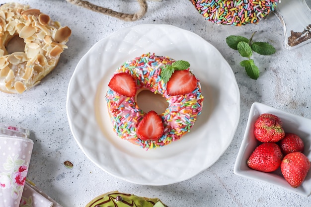 Sweet donut with colored sprinkles and strawberries