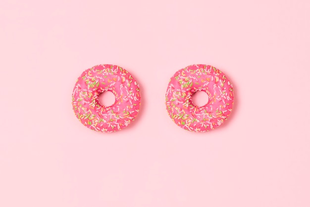 Sweet donuts on pastel pink background Top view flat lay Food concept