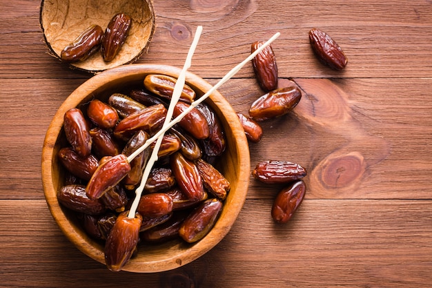 Sweet dried dates fruit in a wooden bowl on the table. Top view