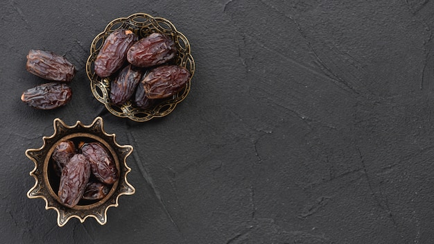 Sweet dry fruit dates in the copper stylish metal bowl on the black surface