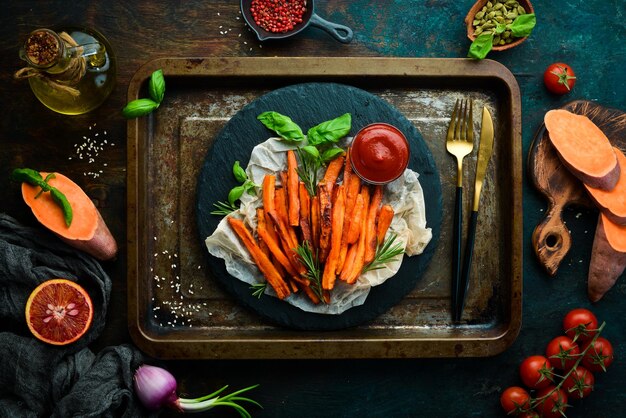 Sweet french fries with ketchup on a black stone plate Top view Free space for your text