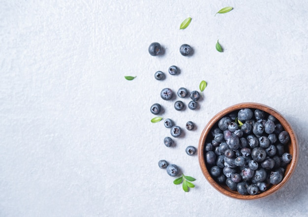 Sweet fresh blueberries in a wooden  bowl  on a blue background. Top view and copy space image