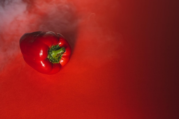 SWEET fresh RED PEPPER ON A RED BACKGROUND WITH A LIGHT SMOKE