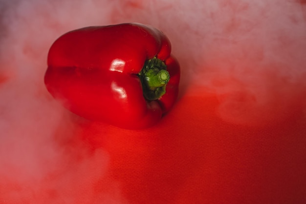 SWEET fresh RED PEPPER ON RED BACKGROUND With smoke around pepper photo for the menu proper nutrition fresh vegetables