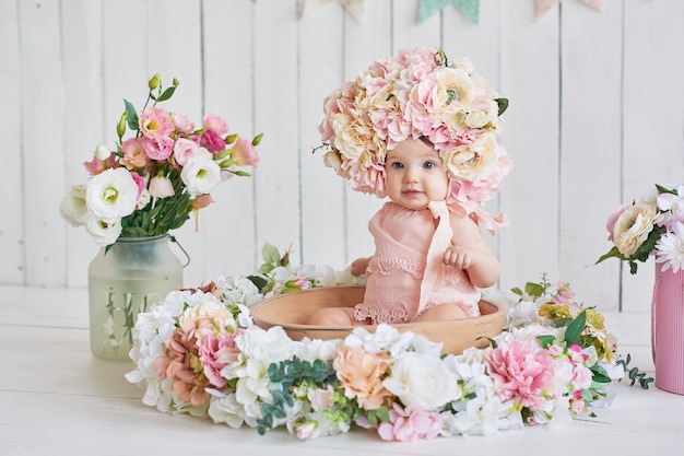 Sweet funny baby in hat with flowers. Easter. Cute baby girl 6 months wearing flower hat.