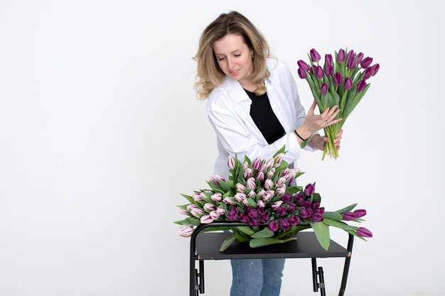 A sweet girl collected a bouquet of different varieties of tulips Stands on a white background