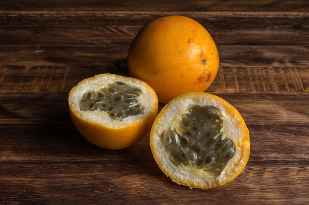 Sweet granadilla or grenadia passion fruit. Whole and cut in half exotic fruits on wooden board