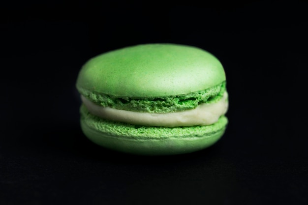 Sweet green macaroon on black background