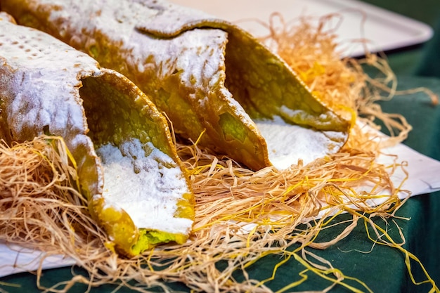 Sweet homemade cannoli stuffed with ricotta cheese cream and pistachial Sicilian dessert at market in Catania Sicily, Italy.