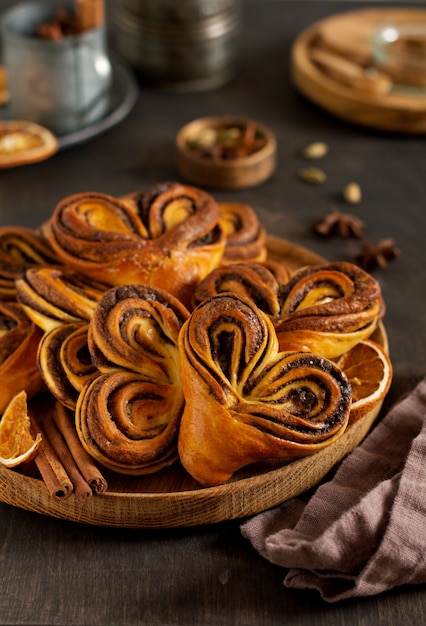 Sweet homemade cinnamon rolls in the shape of a heart on an old retro style. New Year mood