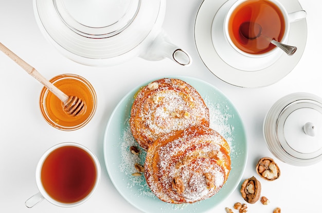 Sweet homemade cinnamon rolls with tea and honey on white. Top view.