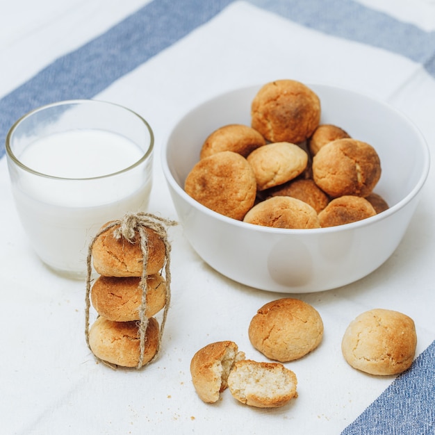 Sweet homemade cookies in bowl and glass of milk on white background, closeup