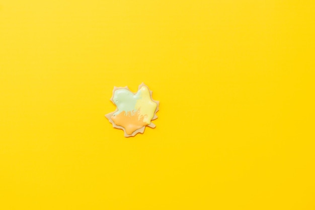 Sweet homemade leaf cookie with icing isolated on yellow background minimal flat lay composition