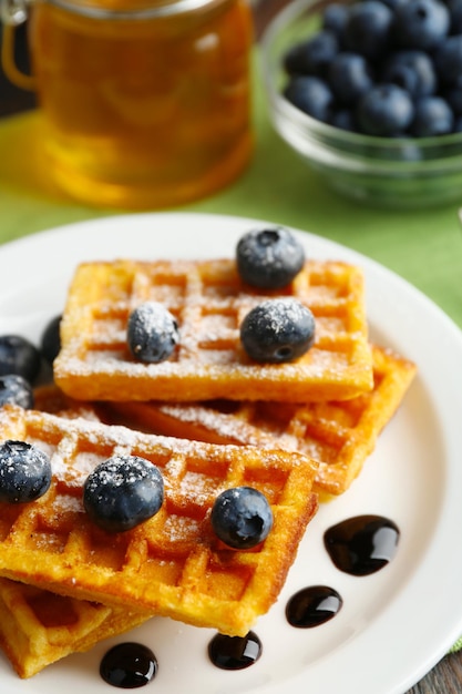 Sweet homemade waffles with forest berries and chocolate sauce on table background