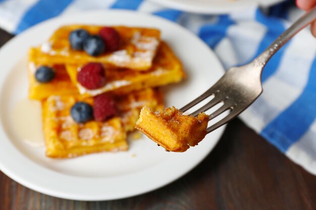 Sweet homemade waffles with forest berries and sauce on table background