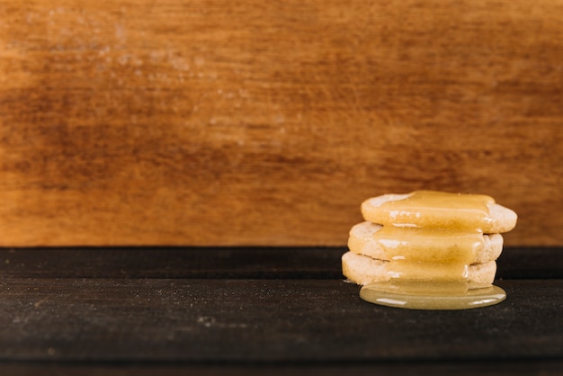 Sweet honey dripping over cookies in front of wooden background