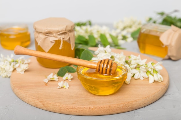 Sweet honey jar surrounded spring acacia blossoms Honey flows from a spoon in a jar jars of clear fresh acacia honey on wooden background