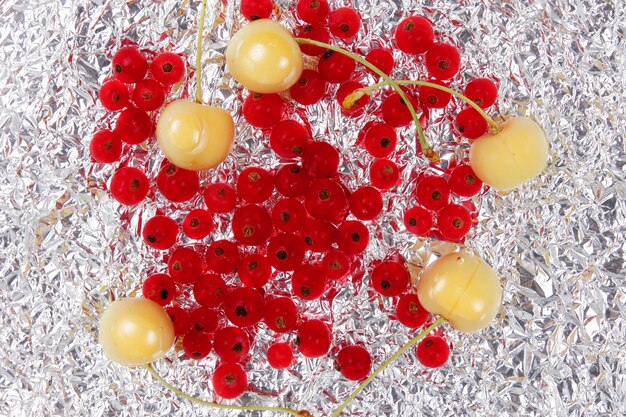 Sweet juicy red currants and yellow cherries on a foil background View from above Vegetarian food concept