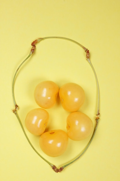 Sweet juicy yellow cherries on a yellow background View from above Vegetarian food concept Closeup