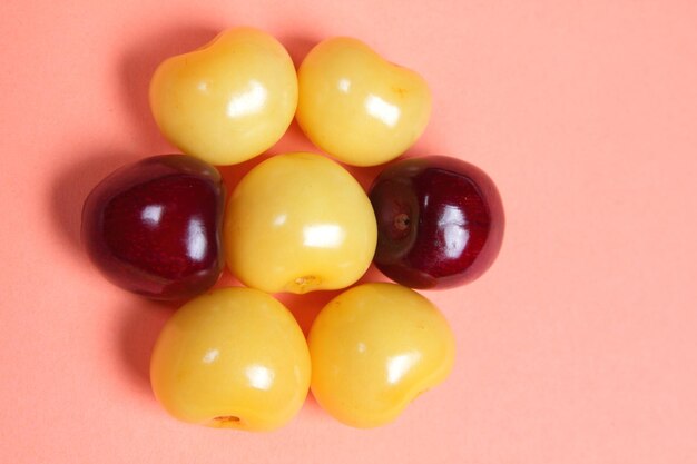 Sweet juicy yellow and red cherries on a pink background View from above Vegetarian food concept Closeup