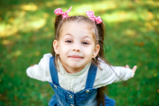 Sweet little girl outdoors with curly hair in two long tails, closeup 