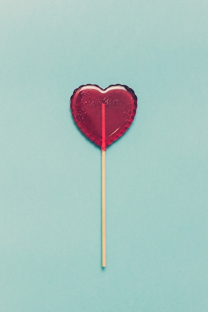 Sweet lollipop on blue background. Red heart. Candy. Love concept. Valentine day