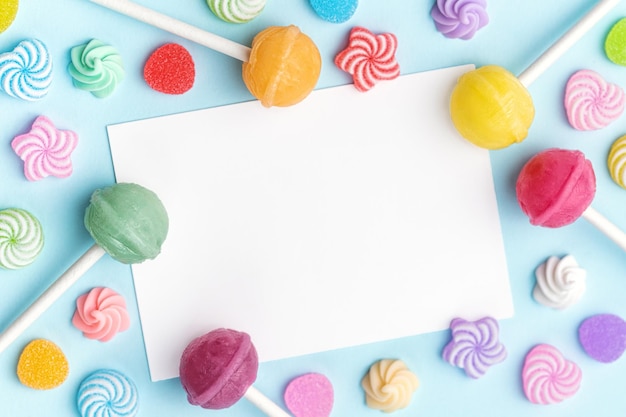 Sweet lollipops and candies and blank greeting card on blue background